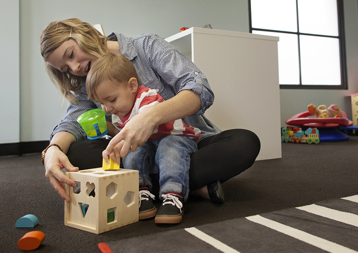 student helping child learn shapes using toy